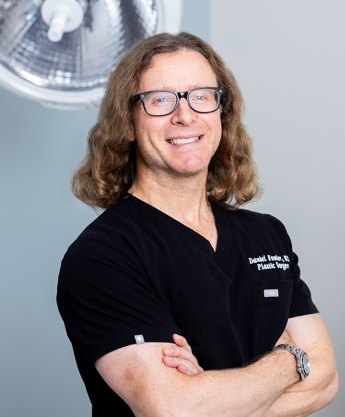 Man with long hair wearing glasses and suit.