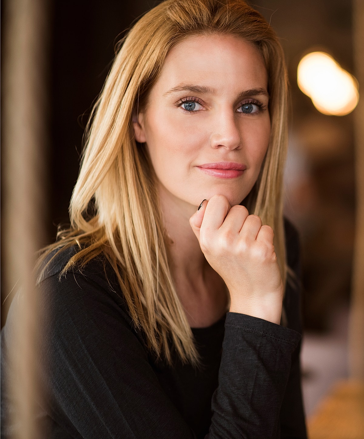 Thoughtful woman with long blonde hair sitting.