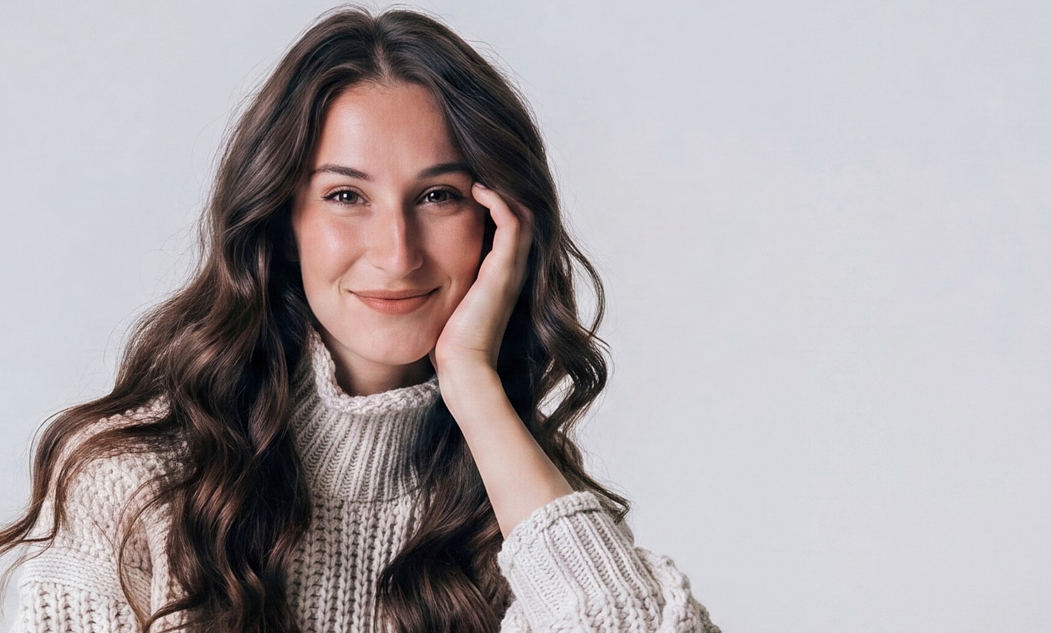 Smiling woman in cozy sweater against light background.